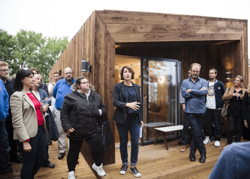 Project leader, Melissa Mean talks to a small crown standing in front of the 'TAM', the low carbon modular home built be the project.